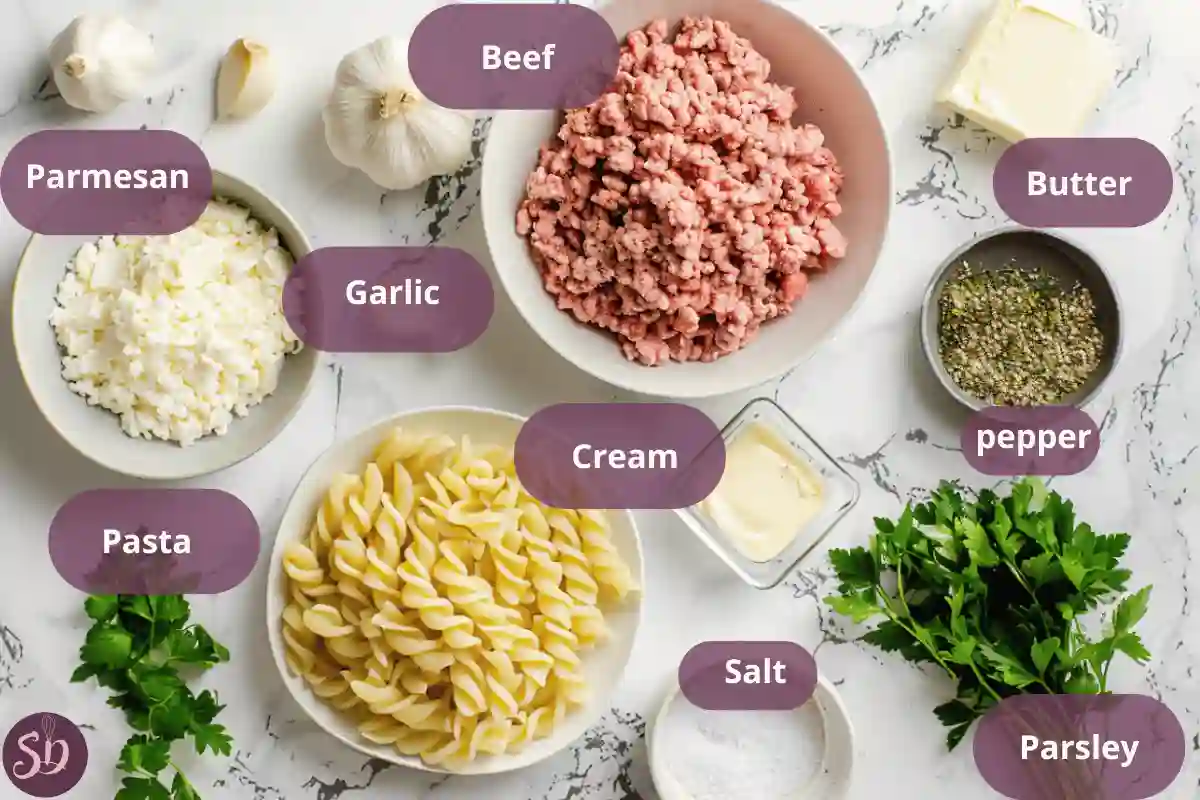  Ingredients for creamy beef and garlic butter pasta laid out on a marble surface, including ground beef, fusilli pasta, cream, butter, garlic, and parmesan cheese.