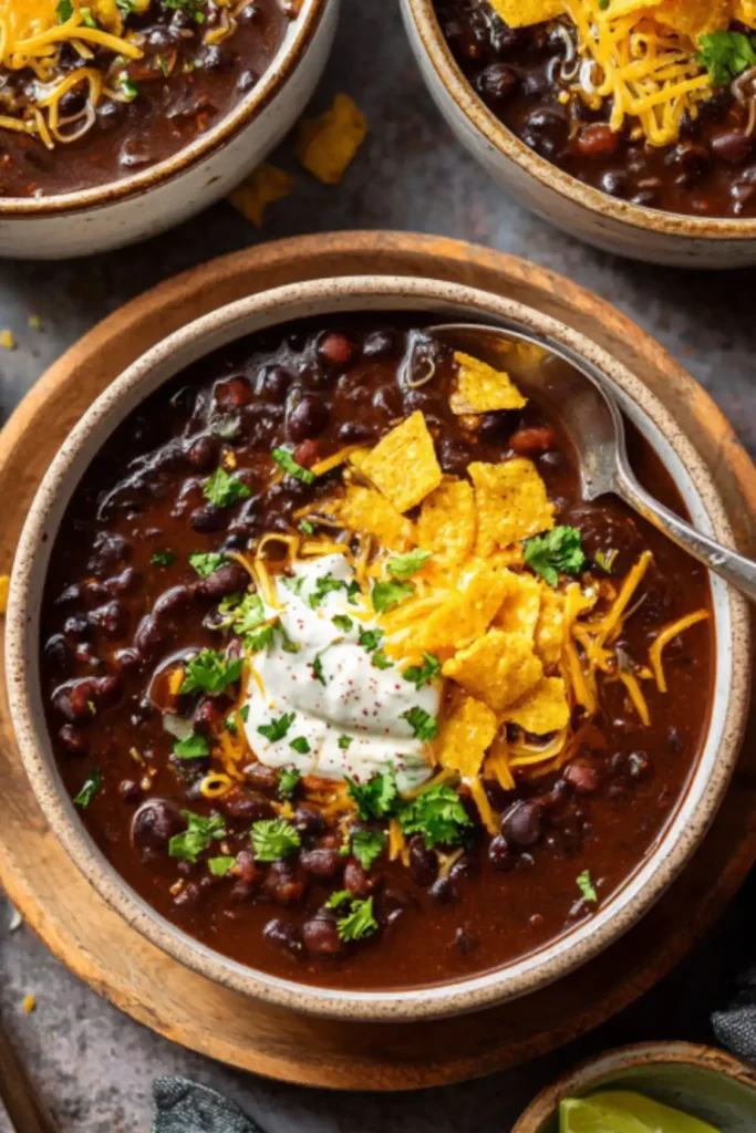 bowl of one pot Mexicali black bean soup topped with cheddar, crema, and tortilla chips