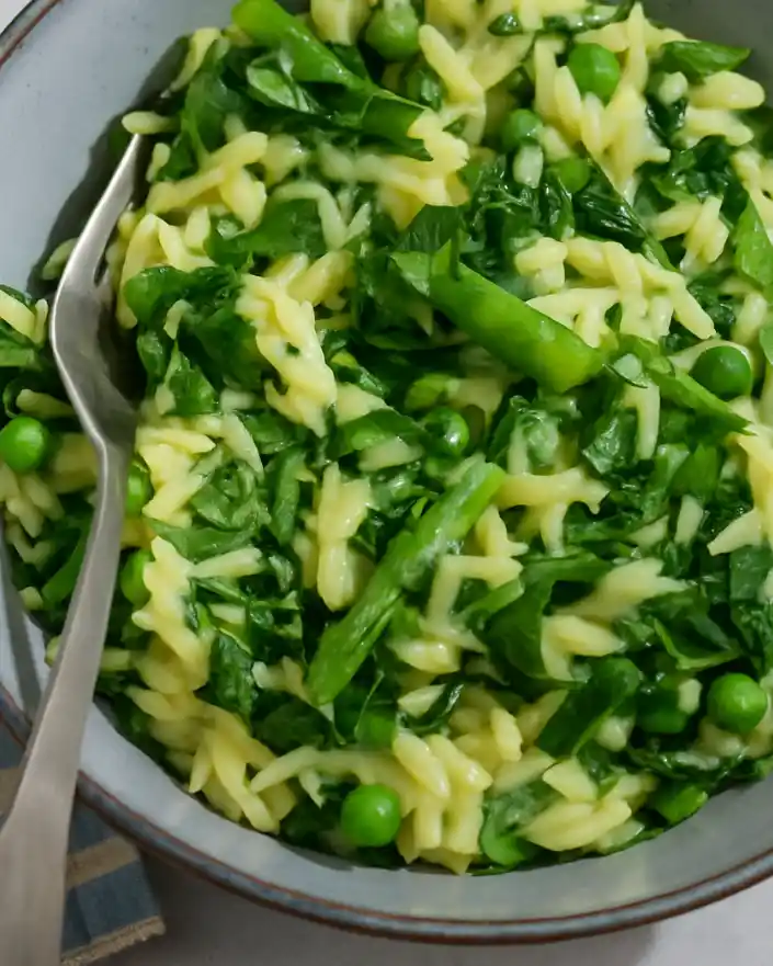 One-pot orzo risotto with spring vegetables topped with ricotta and fresh herbs