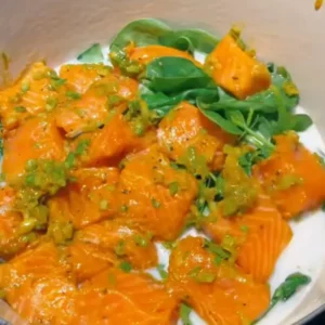 Pieces of marinated salmon arranged in a single layer on top of the spinach in the pot.