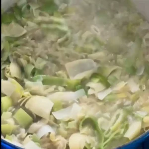 one-pot orzo risotto spring veggies simmering in water in a covered pot.