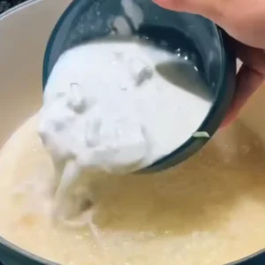 A pot on the stove, filled with rice, coconut milk, and water, beginning to simmer.