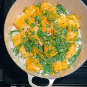 The final one-pot miso salmon dish in the pot, garnished with green onions and lime wedges.