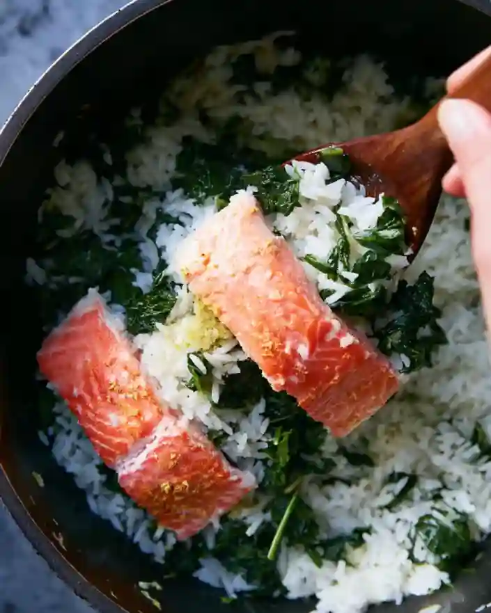 layering salmon over spinach and rice in one-pot recipe