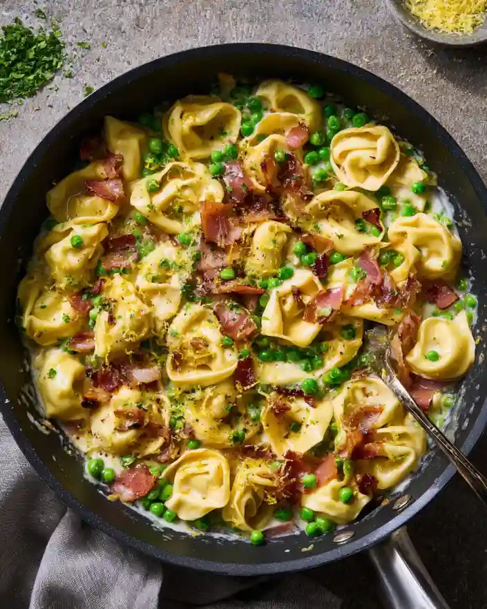 One-pot tortellini with prosciutto and peas in a black skillet