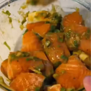 Pieces of raw salmon in a bowl, coated in a bright yellow miso marinade.