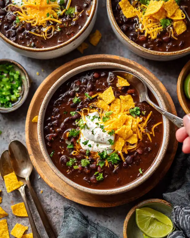 bowl of one pot Mexicali black bean soup topped with cheddar, crema, and tortilla chips