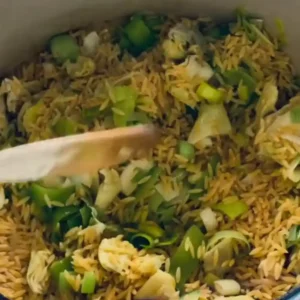 Toasting dry orzo pasta with sautéed leeks in a pot.