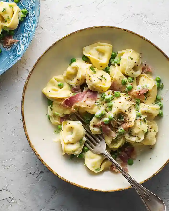 Bowl of creamy tortellini with prosciutto and peas