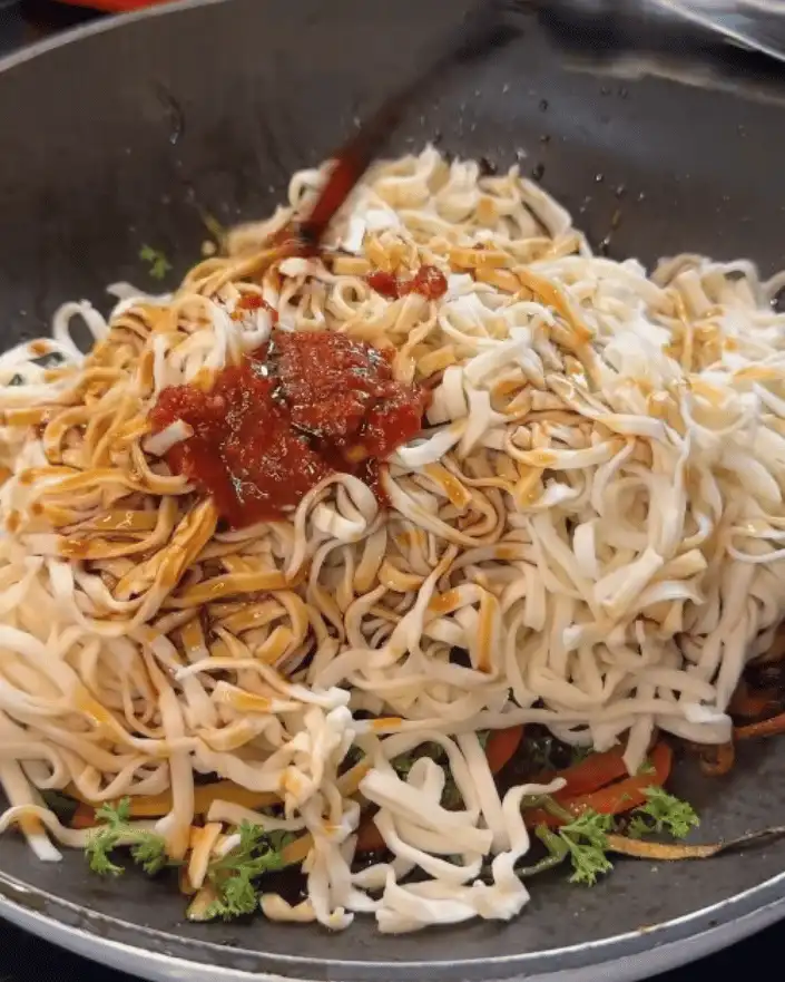 One Pan Chicken with Buttered Noodles Recipe: Adding noodles and sauce to the pan with vegetables