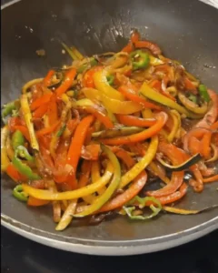 One Pan Chicken with Buttered Noodles Recipe: Sautéing red onion, bell peppers, green chilies, and garlic.