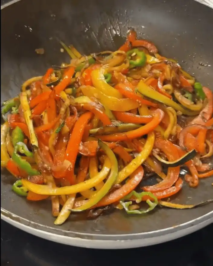 One Pan Chicken with Buttered Noodles Recipe: Sautéing red onion, bell peppers, green chilies, and garlic.
