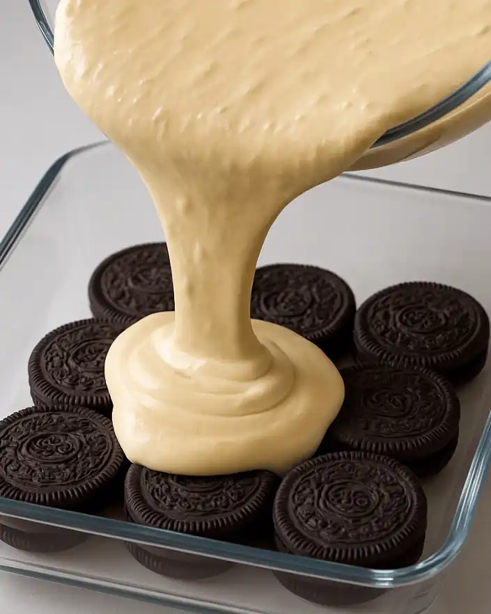 Vanilla cream poured over Oreo cookies in dessert dish