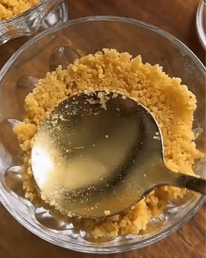 Pressing biscuit crust into serving cup for no bake mango cheesecake cups