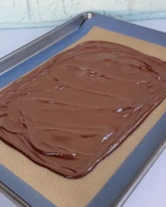 melted chocolate spread on baking sheet for caramel pretzel crack bars