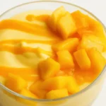 No bake mango cheesecake cup topped with diced mango and sauce