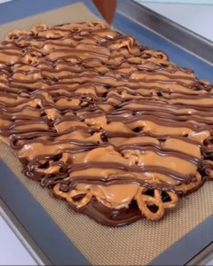 caramel pretzel crack bars with chocolate drizzle on baking sheet