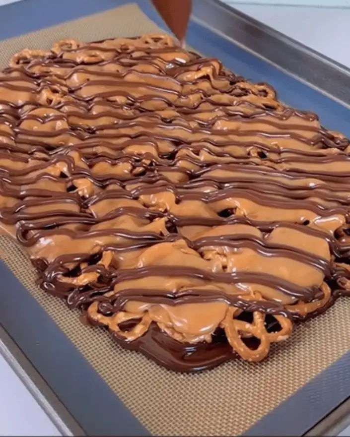 caramel pretzel crack bars with chocolate drizzle on baking sheet