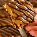hand holding no bake caramel pretzel crack bar with chocolate drizzle