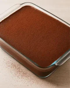 Full tray of no bake Boston cream pie bars dusted with cocoa powder in a glass dish.