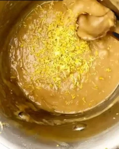 Close-up of lemon zest being mixed into cookie batter for lemon no bake oatmeal cookies in a saucepan.