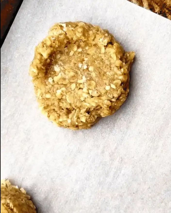 Uncoated lemon no bake oatmeal cookie resting on a baking sheet lined with parchment paper.