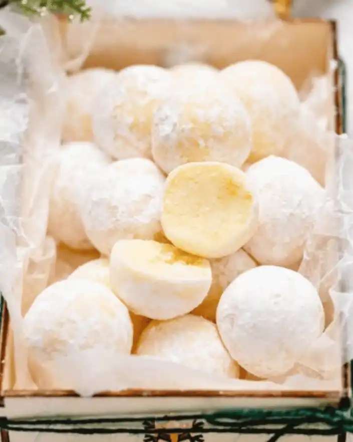 no bake orange creamsicle truffles in a gift box with powdered sugar coating