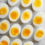 How to Hard Boil Eggs 3 Hard Boil Eggs sliced in half showing firm golden yolks on a white plate