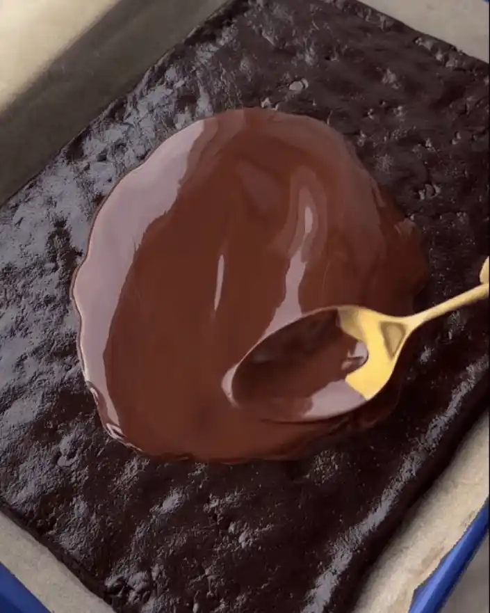 Spreading melted chocolate topping over no bake healthier brownies recipe