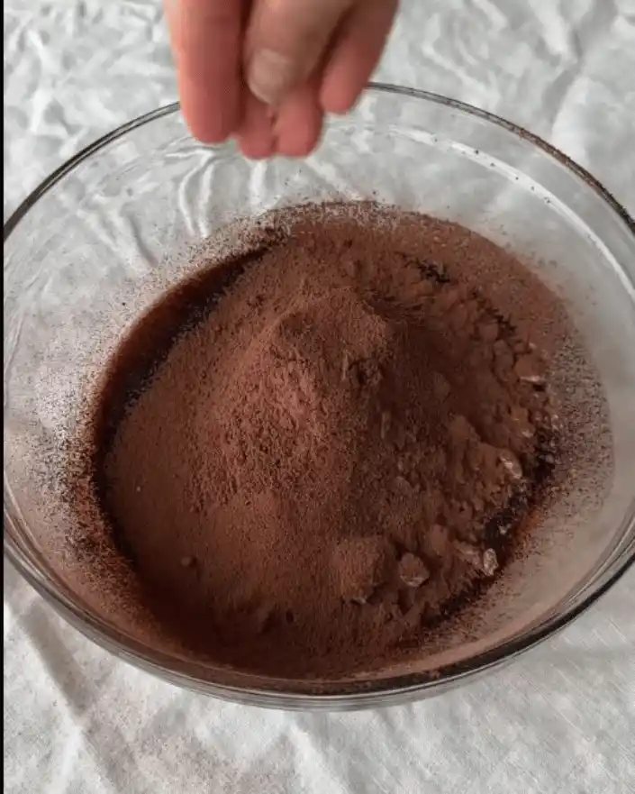 Mixing cocoa powder, maple syrup, and peanut butter for no bake healthier brownies recipe