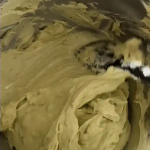 Mixing creamy pistachio cheesecake filling in a bowl