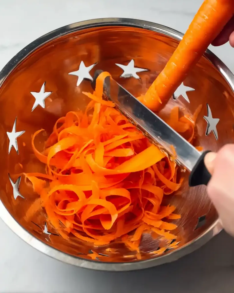 Shaving fresh carrots into ribbons with a Y-peeler for carrot ribbon salad