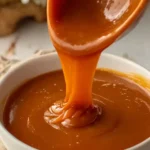 Homemade Caramel Sauce 2 Homemade caramel sauce dripping from spoon into glass jar